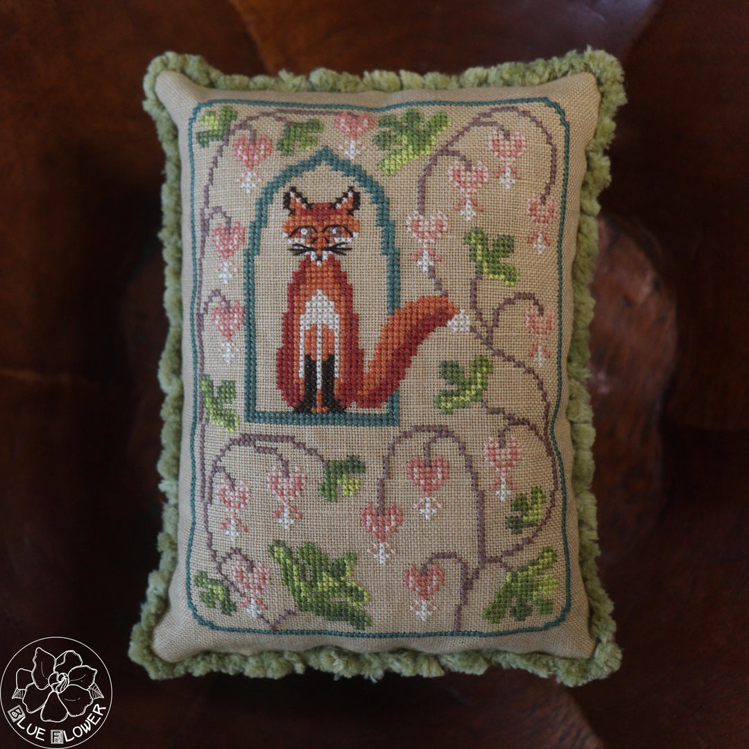 Embroidered pillow with a fox design on a brown surface