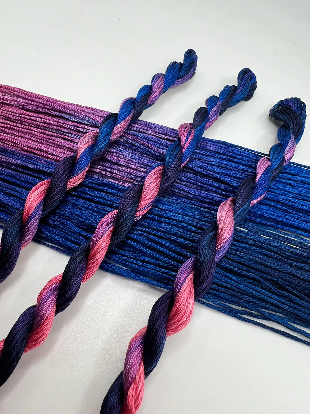 Braided blue and pink embroidery floss skeins on a white background