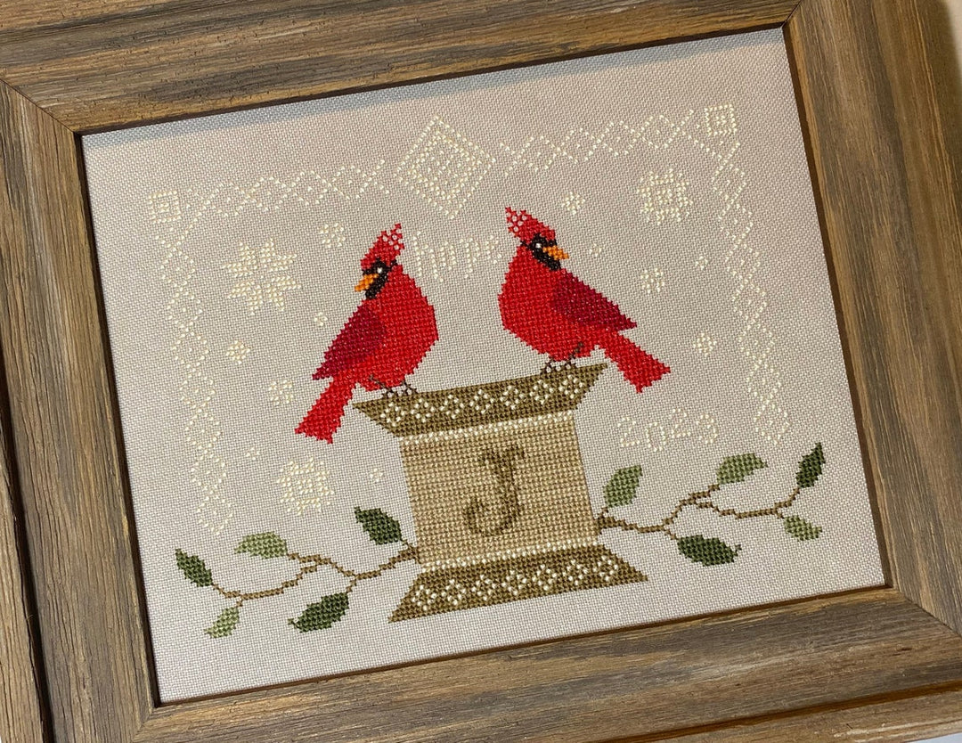 two red cardinals perch on a spool