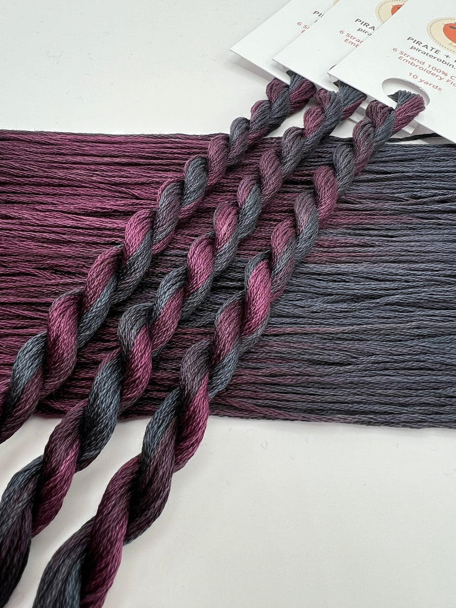 Two skeins of yarn with purple and gray gradient on a white background