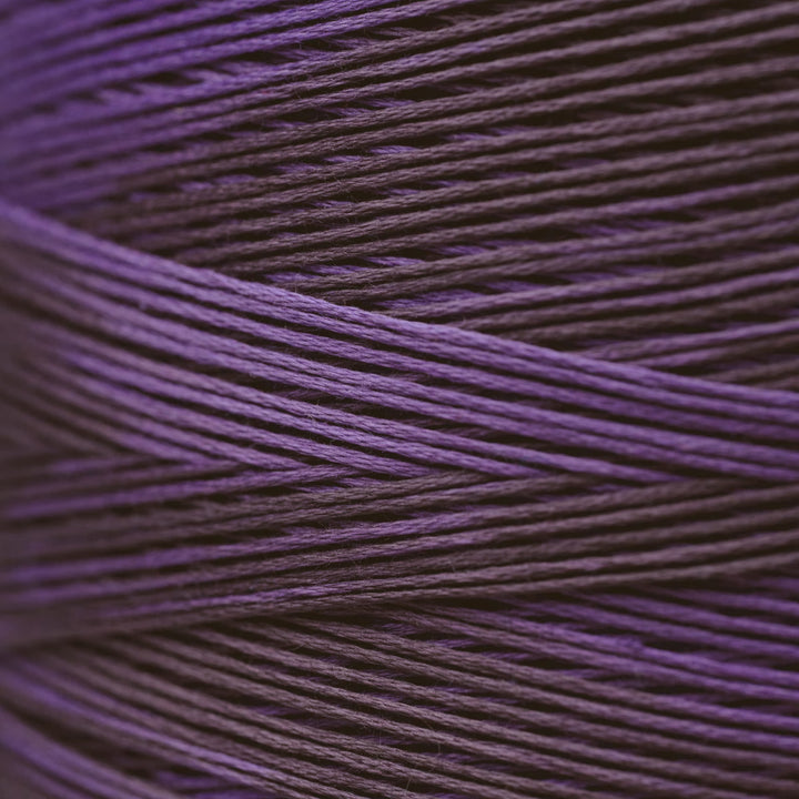 A close-up of tightly wound thread in a deep purple color, filling the entire frame.