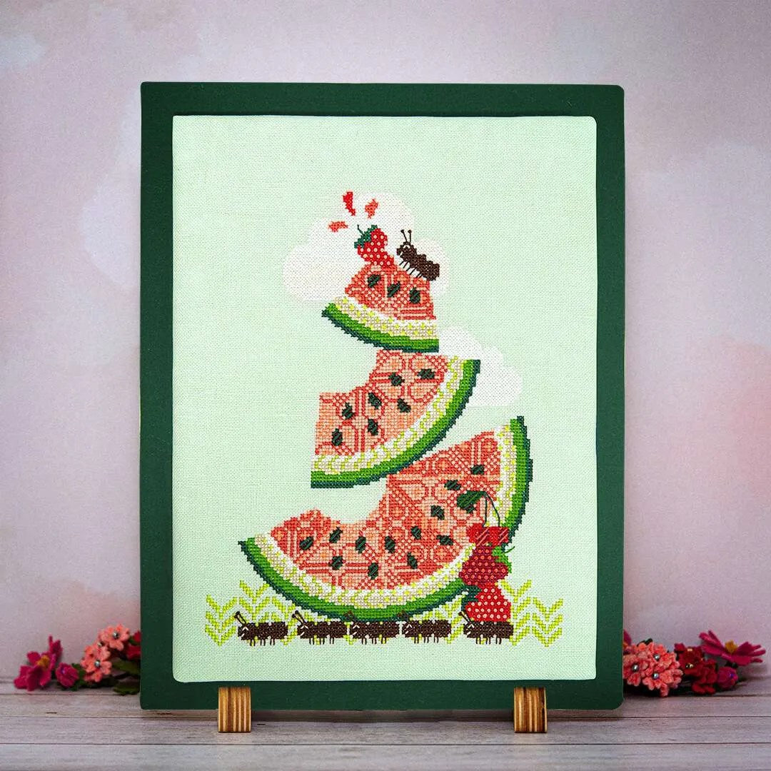 Cross-stitched watermelon design on a light green fabric with a green frame.