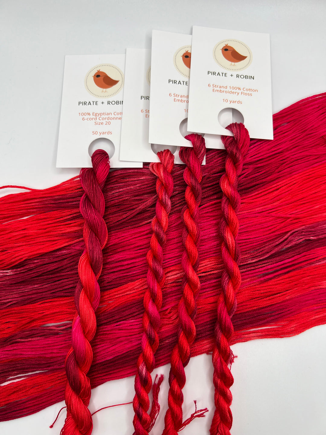 Red braided embroidery floss with brand labels on a white background