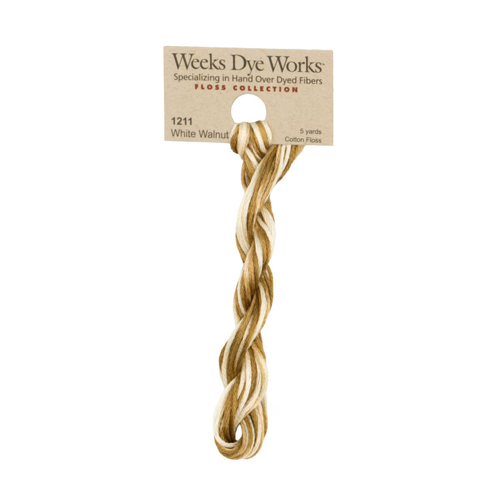 A single twisted bundle of Weeks Dye Works White Walnut cotton floss, showing a blend of off-white and light golden-brown tones, attached to its original kraft paper packaging card against a plain white background.
