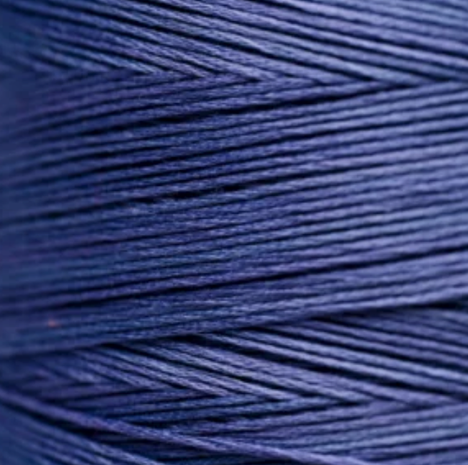 A close-up of tightly wound thread in a deep navy blue color, filling the entire frame.