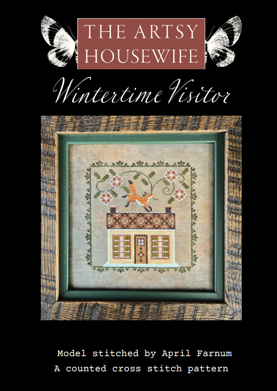 Cover of 'Wintertime Visitor' cross stitch pattern by The Artsy Housewife, featuring a framed stitched design of a house with a bird and floral border on a black background.