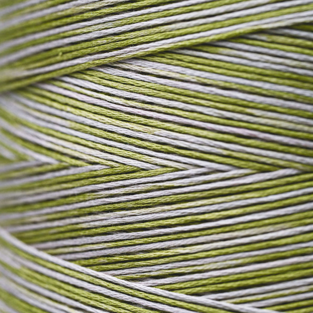 Close-up of variegated thread wound in a cone, showing alternating stripes of olive green and white.