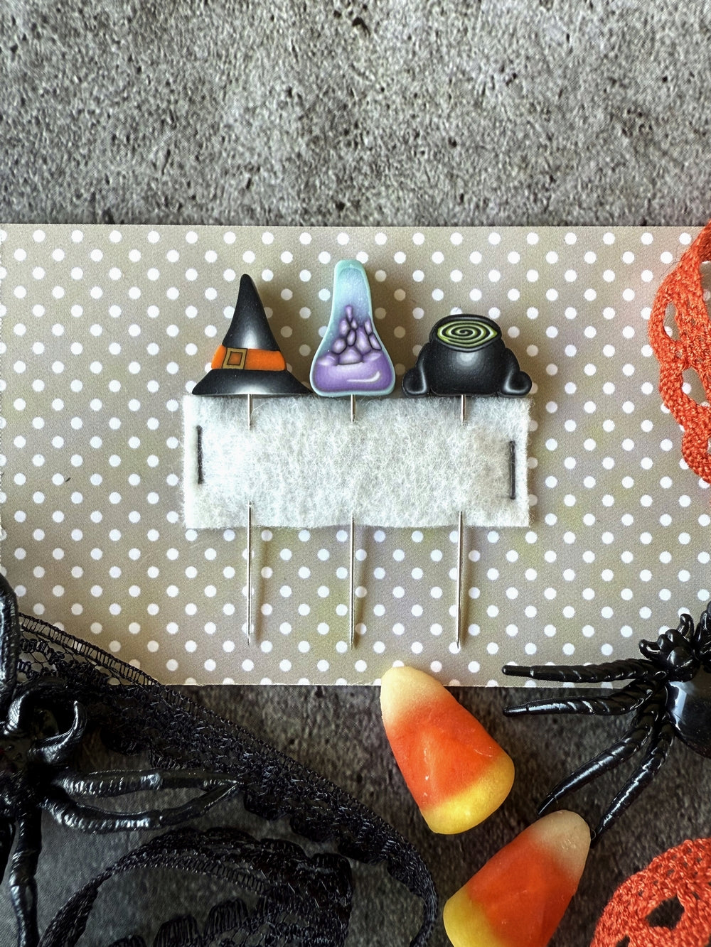 Halloween-themed decorative pins on a polka dot background with candy corn and spider decorations.