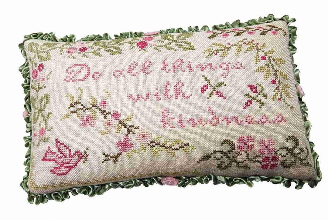 Decorative pillow with embroidered text and floral patterns on a white background