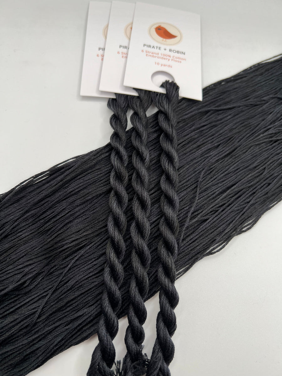 Black braided skeins of embroidery thread with brand labels on a white background