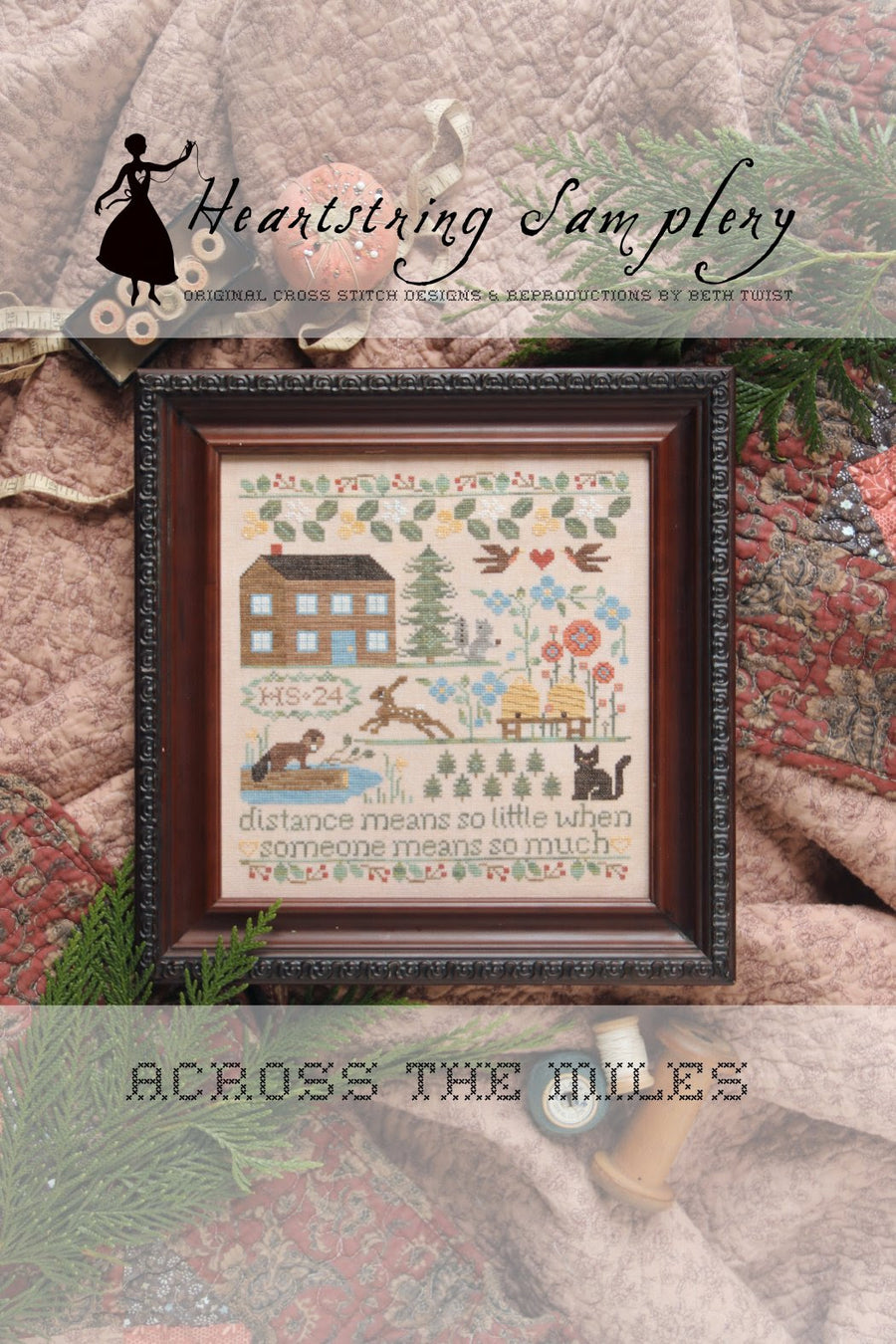 Framed cross-stitched sampler with scenic design and text, featuring 'Heartstring Samplery' branding.