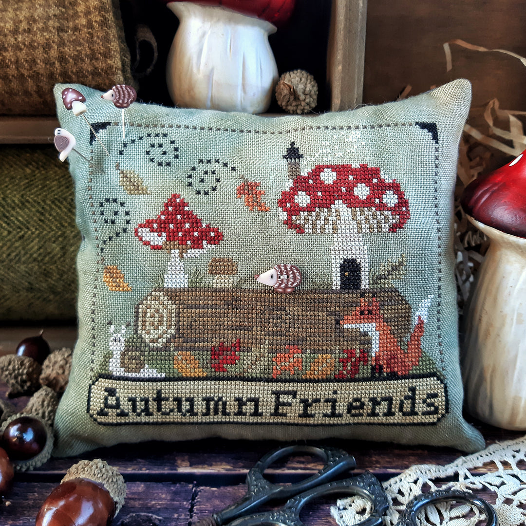 pincushion showing  log with autumn leaves and redcapped mushrooms and a fox and snail