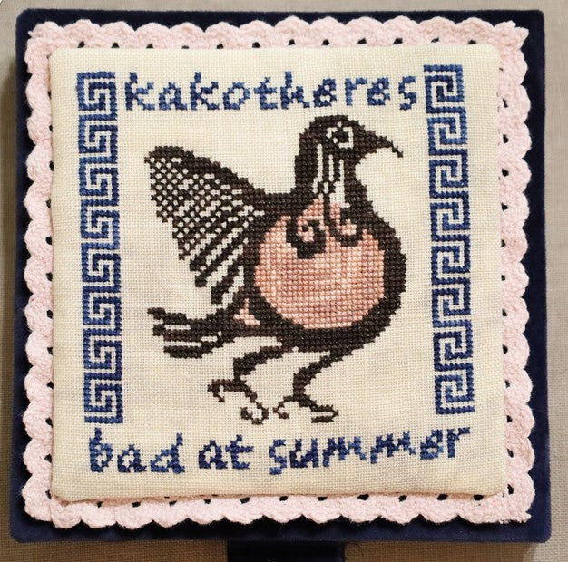Embroidered pillow with a bird design and text on a plain background