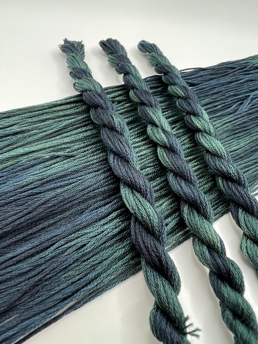 Close-up of skeins of blue green floss  on a white background