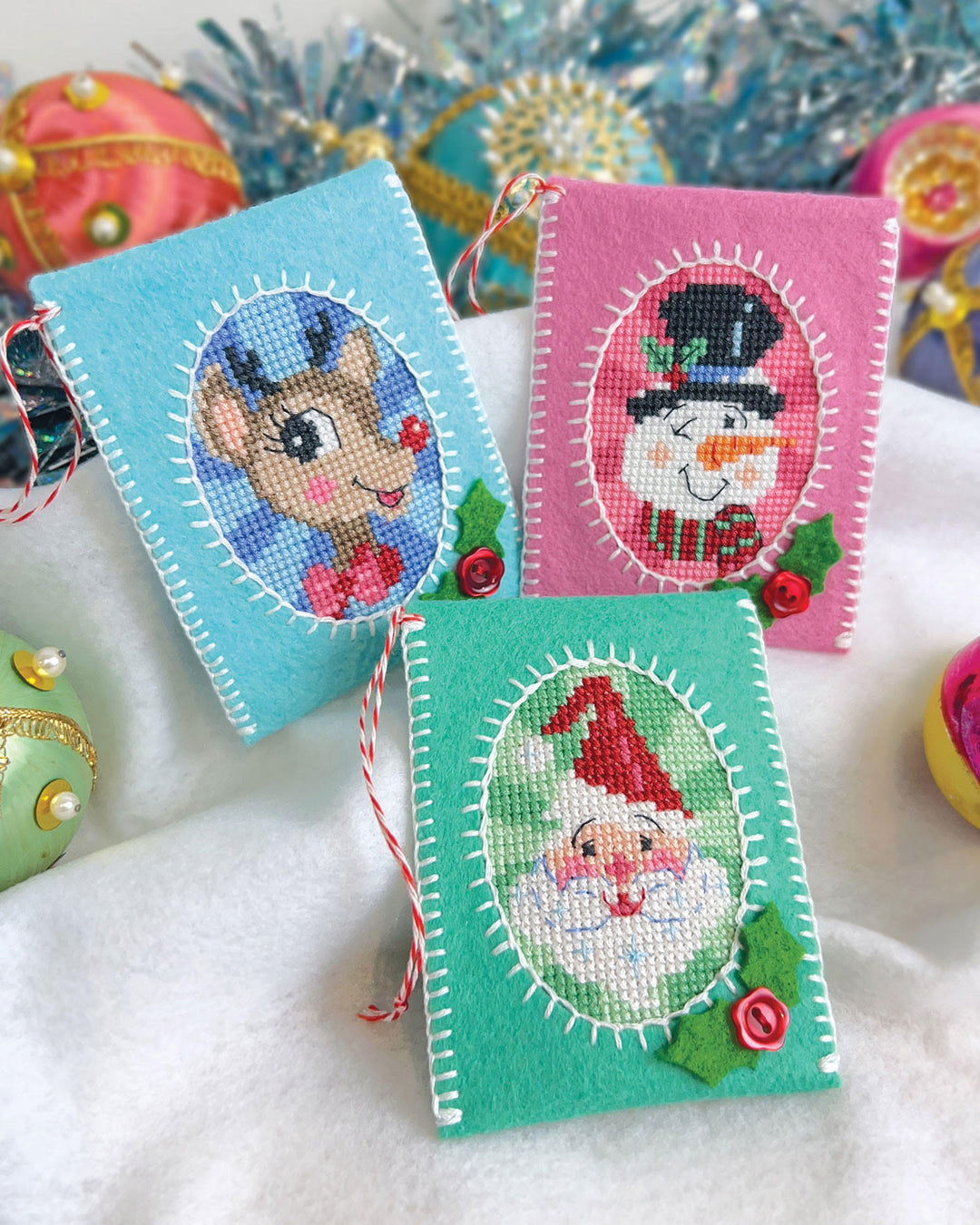 Three embroidered Christmas-themed cards with reindeer, snowman, and gnome designs on a snowy background.