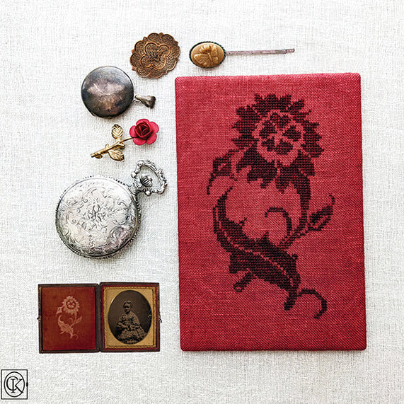 Cross stitch pattern with red fabric and decorative elements on a white background