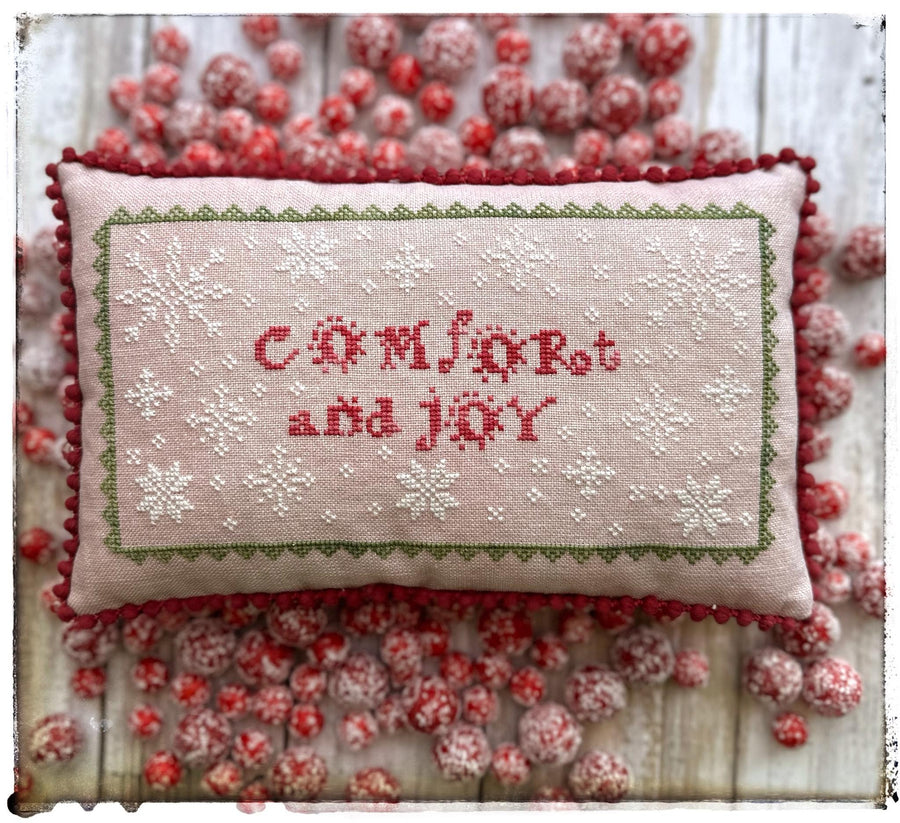 Decorative pillow with 'Comfort and Joy' text surrounded by red berries on a white background