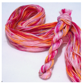 Colorful pink and orange thread skeinon a white background