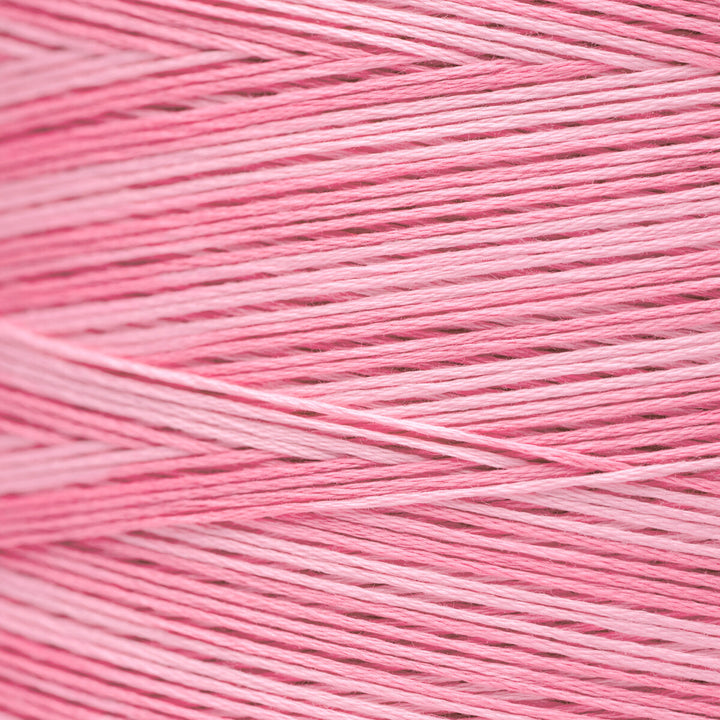 A close-up of pink yarn strands wound together, showing the texture and color of the thread.