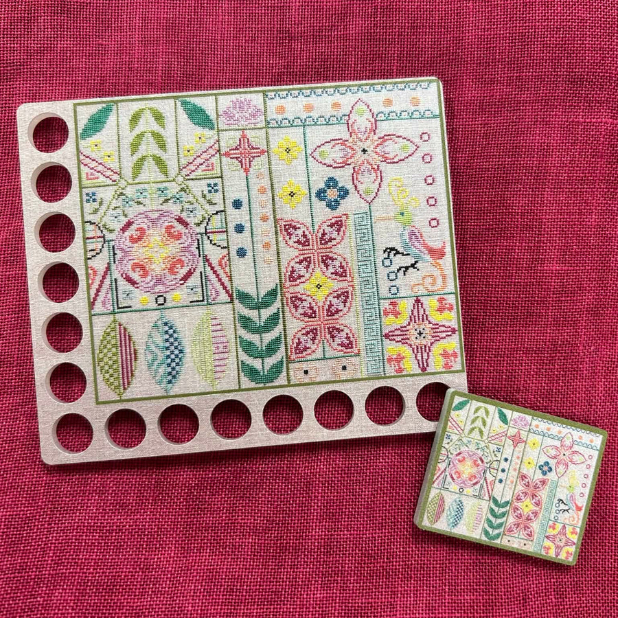 Colorful embroidery patterns on a wooden board and fabric swatch against a red background