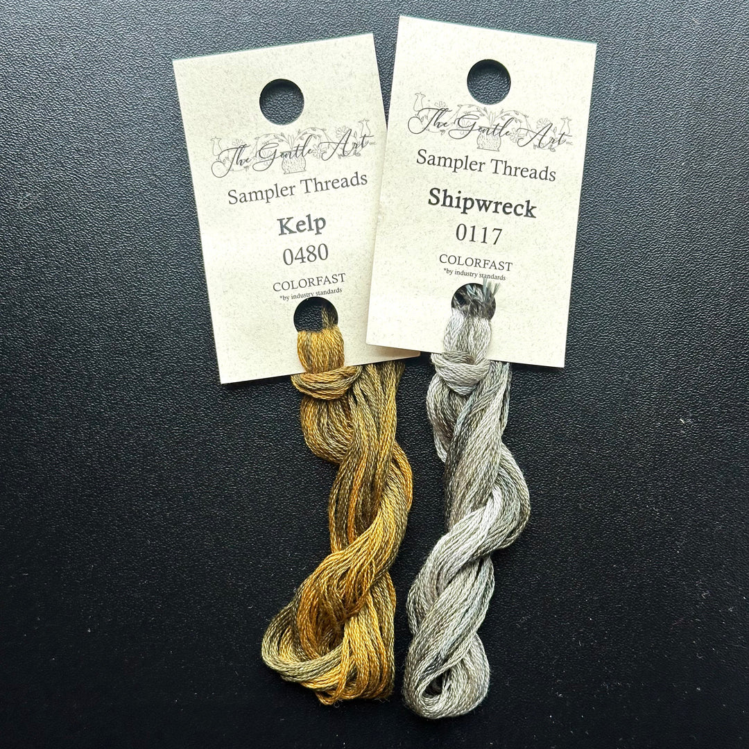Two skeins of embroidery thread, one labeled 'Kelp' and the other 'Shipwreck', on a dark background with labels.