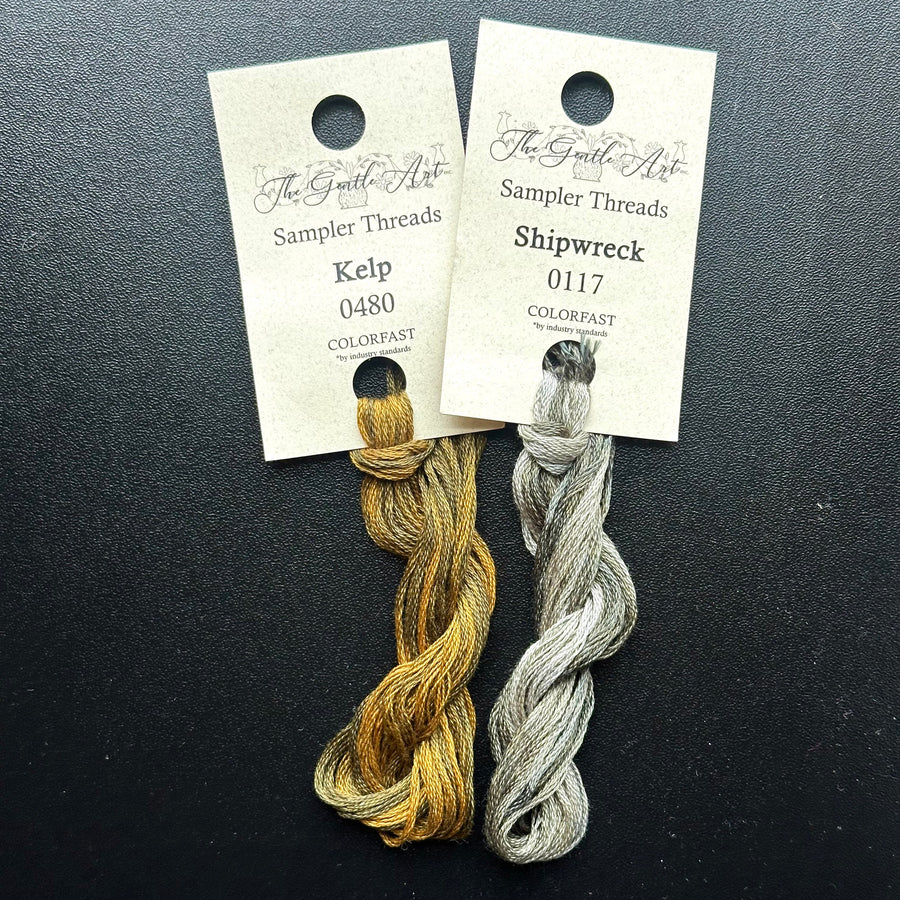 Two skeins of embroidery thread, one labeled 'Kelp' and the other 'Shipwreck', on a dark background with labels.