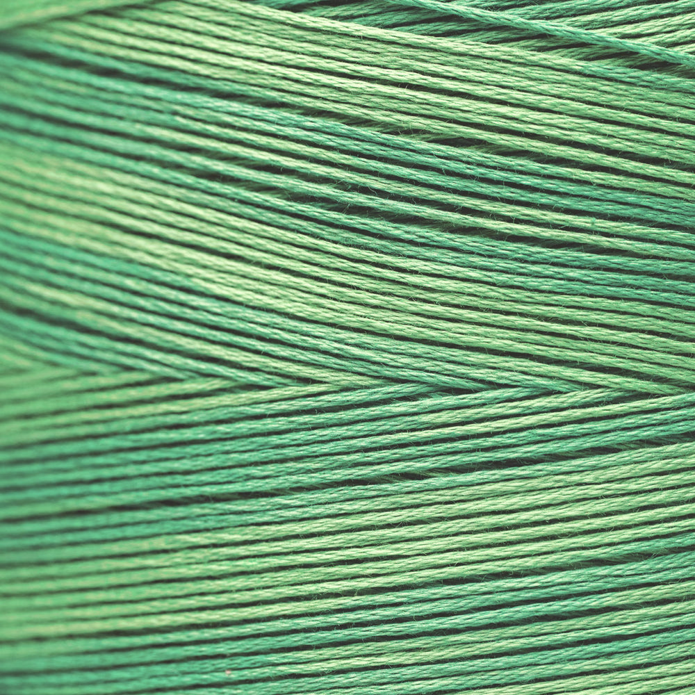 A close-up of tightly wound thread or cord in a green color, showing the texture and pattern of the strands.