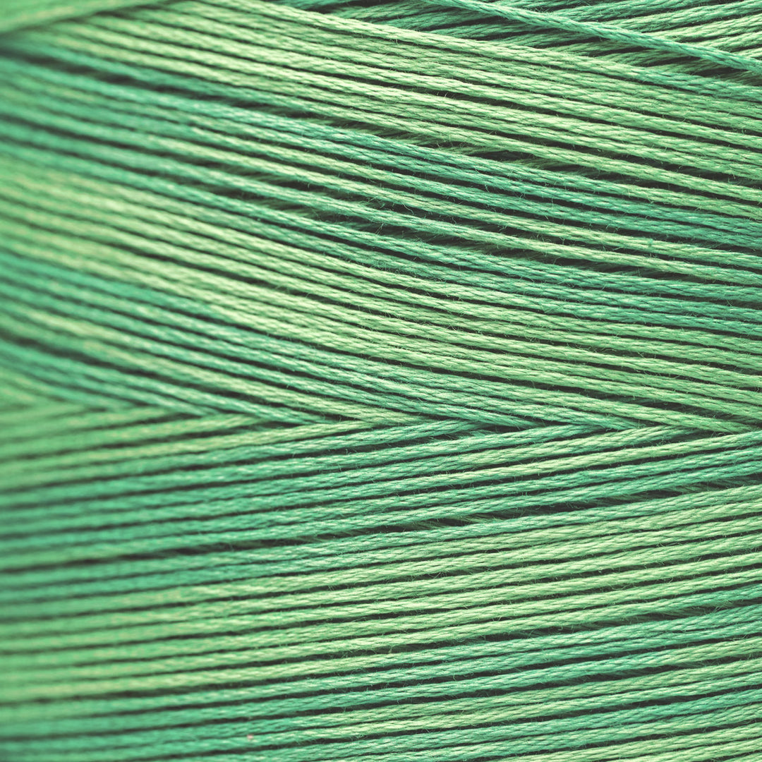 A close-up of tightly wound thread or cord in a green color, showing the texture and pattern of the strands.