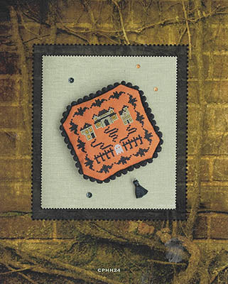 Embroidered design on fabric with a decorative border against a textured brown background