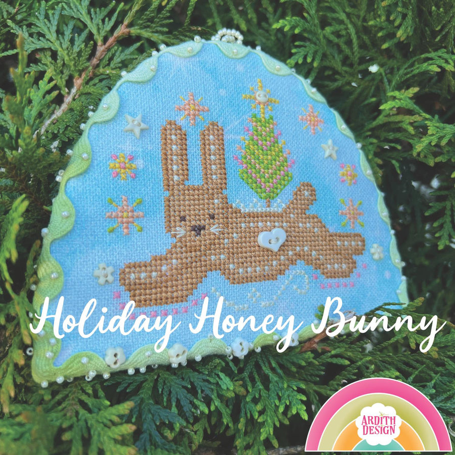 Cross-stitched bunny ornament with 'Holiday Honey Bunny' text on a green leaf background