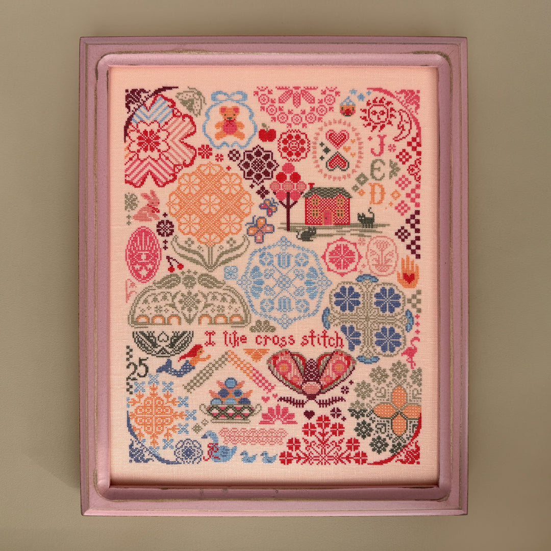 Framed cross-stitch pattern with colorful designs on a beige background