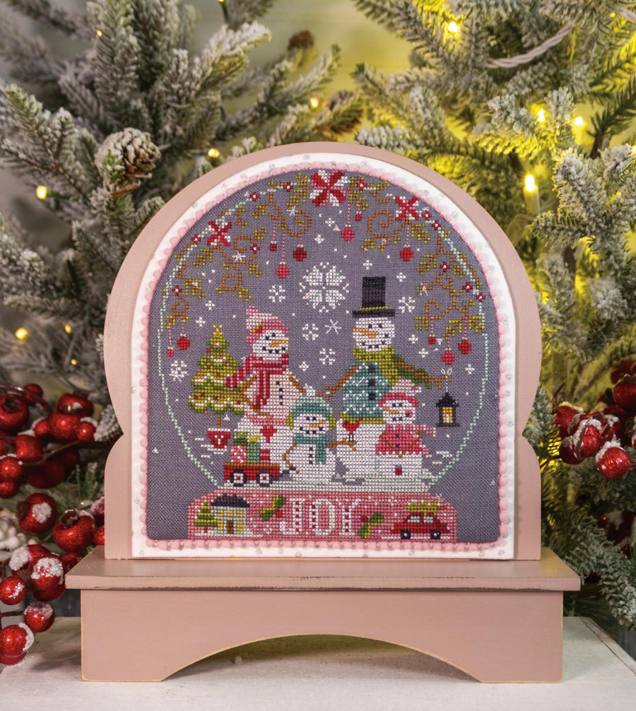 Cross-stitched snow globe design with Christmas-themed elements on a tree background, featuring 'Peppermint Lane' by Peppermint Lane.
