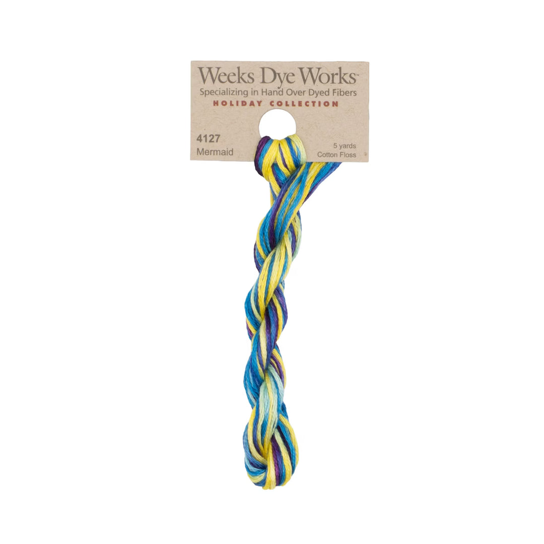 A twisted braided fiber rope in a multicolor mermaid pattern of blue, yellow, and white, attached to a brown paper header card from Weeks Dye Works Holiday Collection.