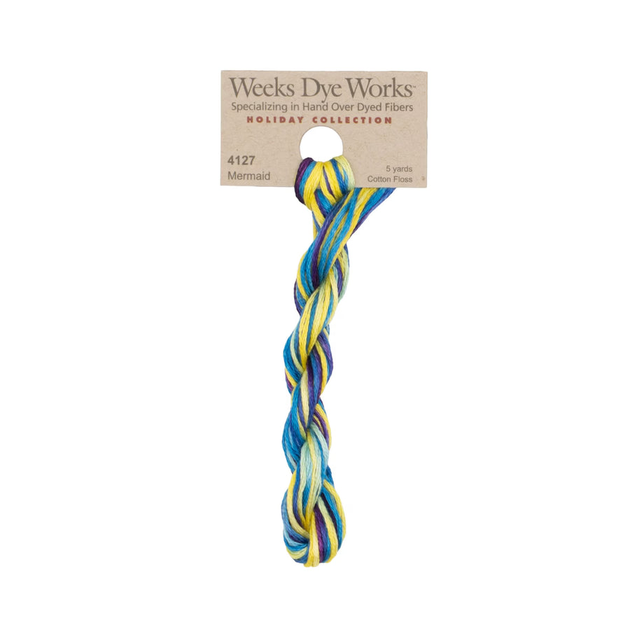 A twisted braided fiber rope in a multicolor mermaid pattern of blue, yellow, and white, attached to a brown paper header card from Weeks Dye Works Holiday Collection.