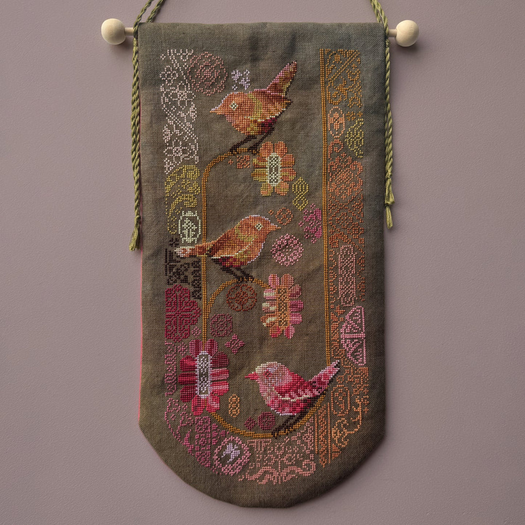 Decorative tapestry with embroidered birds and floral patterns on a brown background
