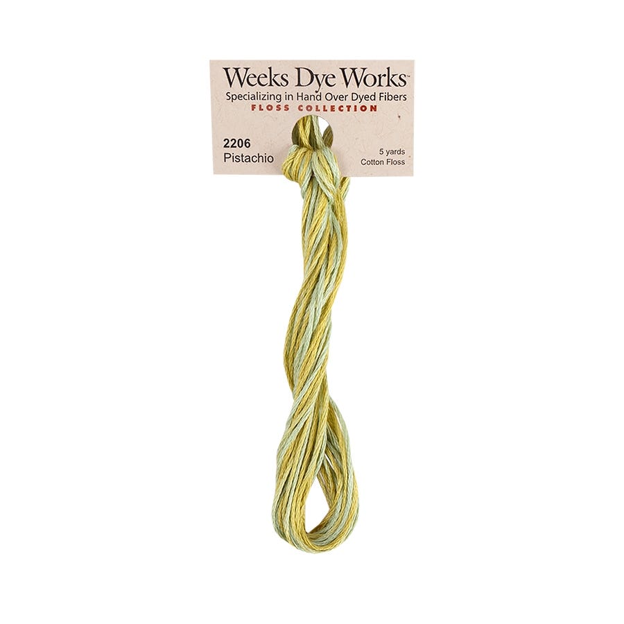 A skein of Weeks Dye Works Pistachio cotton floss thread, showing a soft yellow-green color, attached to its original paper label card against a plain white background.