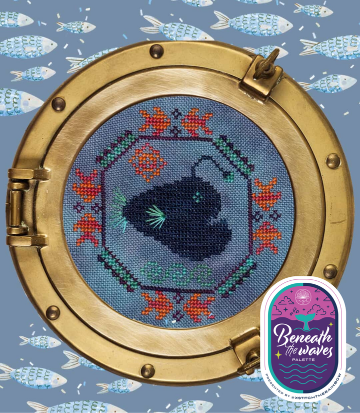 Decorative needlepoint with fish design inside a brass porthole on a blue background with fish illustrations.