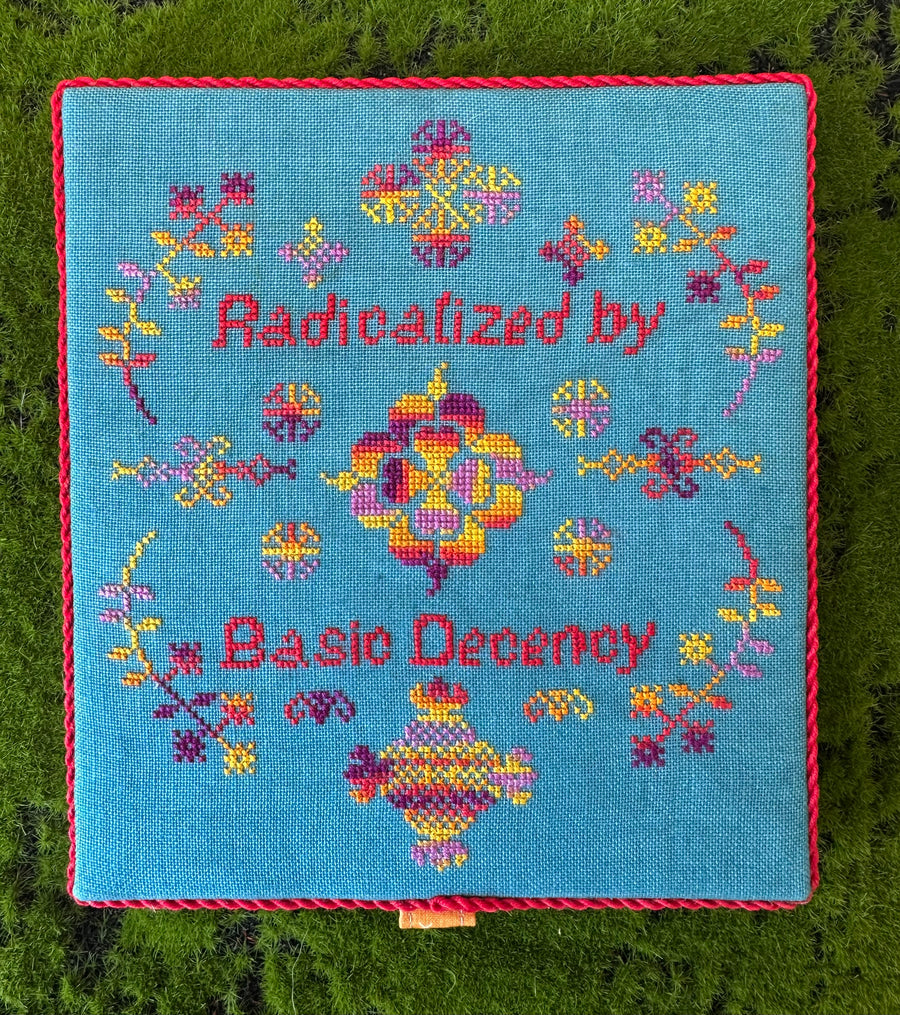 Embroidered square with floral patterns and text on a blue background