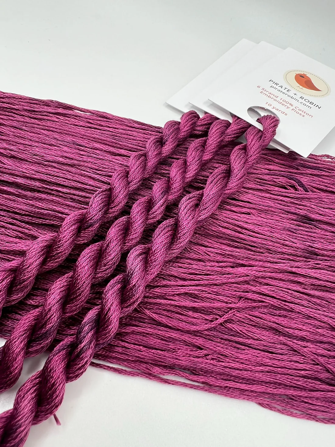 Purple thread skein with a brand label on a white background