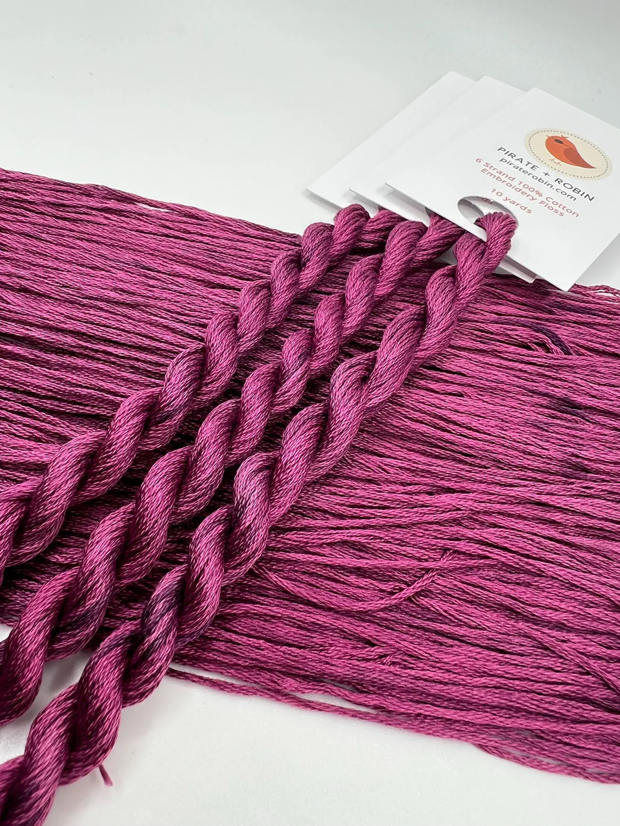 Purple thread skein with a brand label on a white background