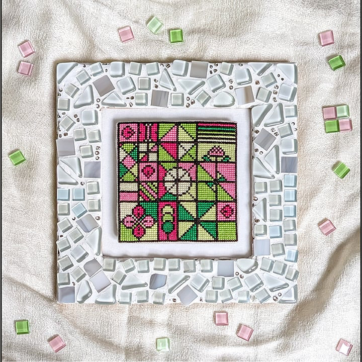 A counted cross stitch PDF pattern preview titled 'Spring Mosaic' showing a completed square mosaic design with pink, green, and gray geometric tiles on a white fabric background, with side text reading 'COUNTED CROSSTITCH PDF PATTERN' and 'SPRING MOSAIC'.