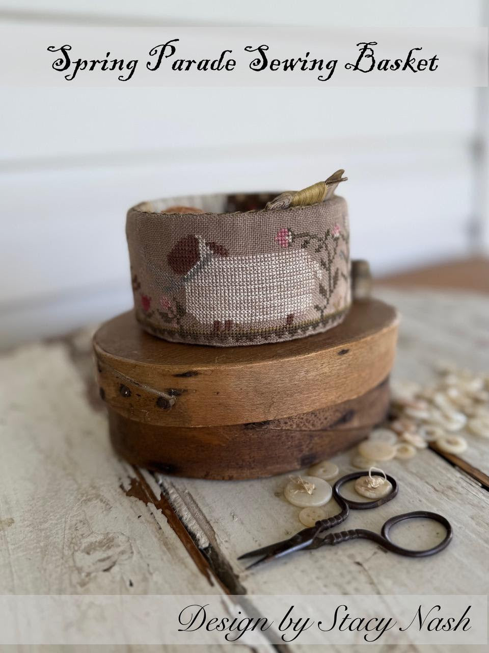 Sewing basket with embroidery and vintage scissors on a wooden surface, designed by Stacy Nash.