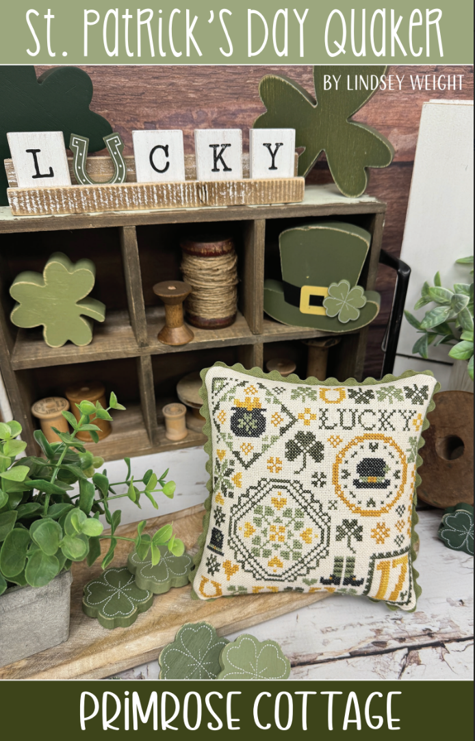 A cross-stitch pattern display featuring a green and white themed design with the words 'LUCKY', shamrocks, and a depiction of a pot with gold.