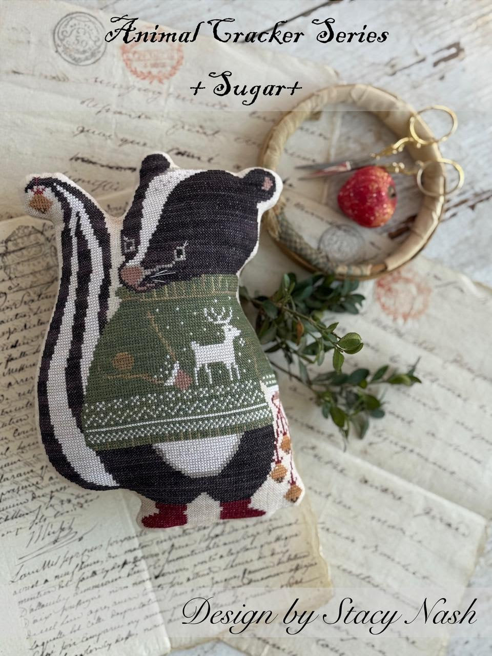 Decorative skunk cross stitch pillow wearing a sweater with a design, on a textured surface.