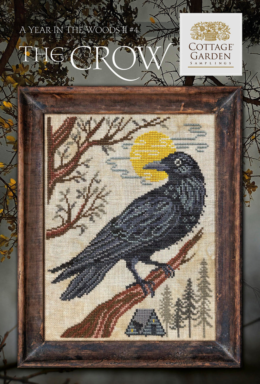 Framed cross-stitched artwork of a crow on a branch with a moonlit sky, featuring the Cottage Garden Company logo.