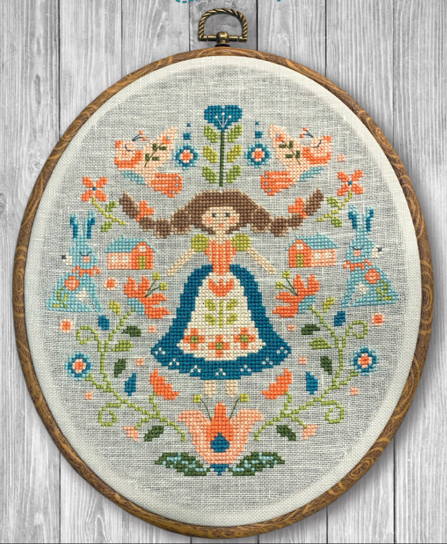 Embroidery hoop with a colorful floral and figure design on a wooden surface