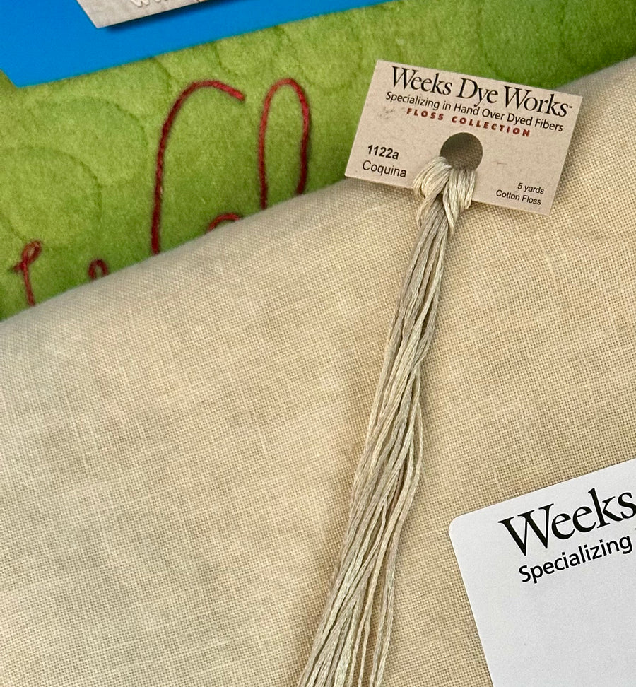 Thread spool with Weeks Dye Works label on a fabric background