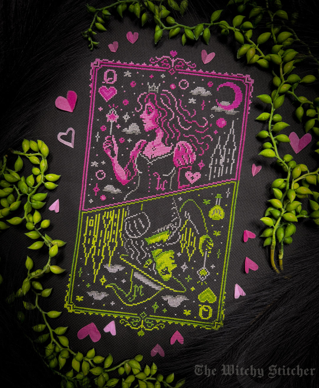 A tarot card design featuring the Queen of Witches, split into two halves with pink and lime green embroidery on a black background, surrounded by green leaves and pink hearts. The brand name 'The Witchy Stitcher' is visible in the bottom right corner.