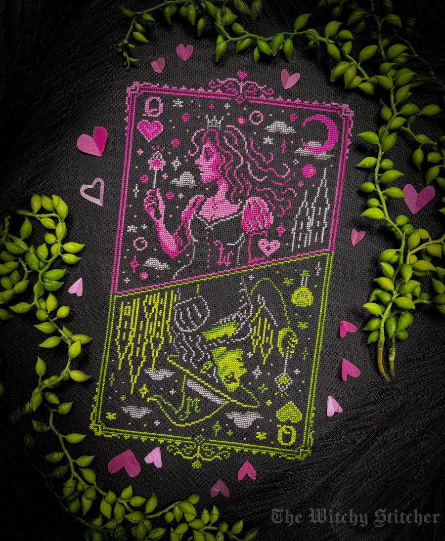 A tarot card design featuring the Queen of Witches, split into two halves with pink and lime green embroidery on a black background, surrounded by green leaves and pink hearts. The brand name 'The Witchy Stitcher' is visible in the bottom right corner.
