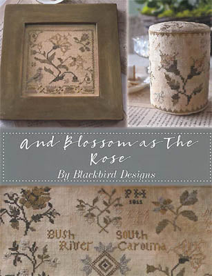 Cross-stitched design with floral patterns and a framed piece on a textured surface.